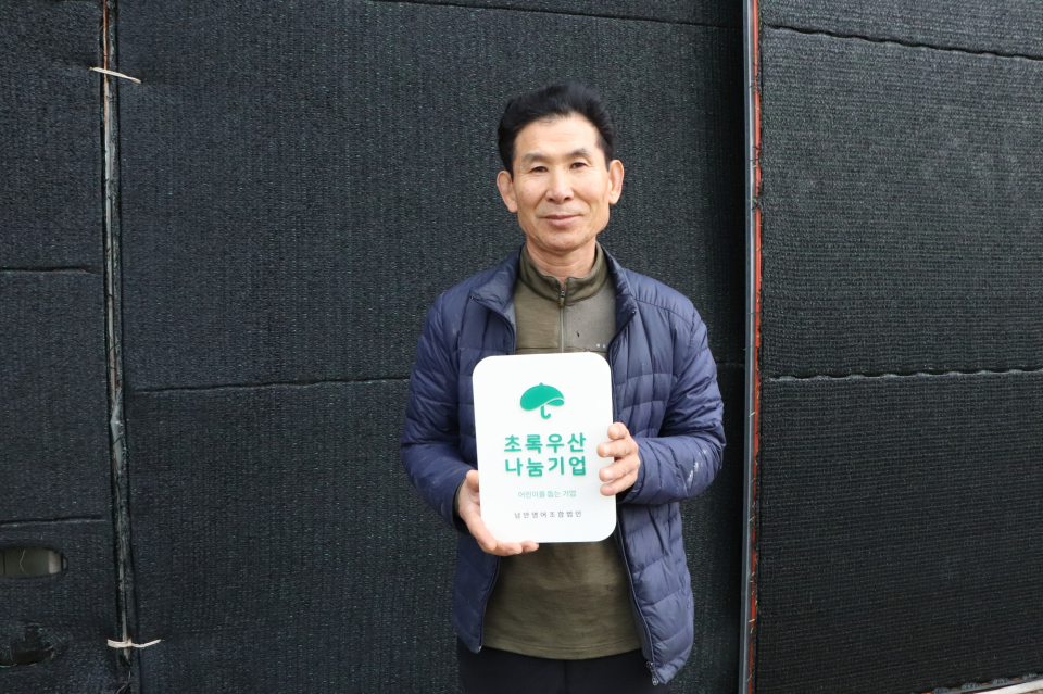 서귀포시 대정읍에 위치한 남안영어조합법인에서 김일환 대표가 나눔현판을 들고 사진촬영을 하고 있다.